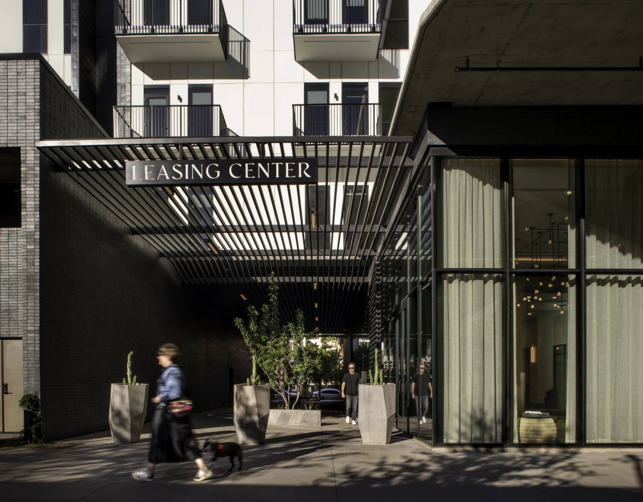 Leasing center entrance recessed into a mixed-use residential building with glazed storefronts and pedestrian-oriented design