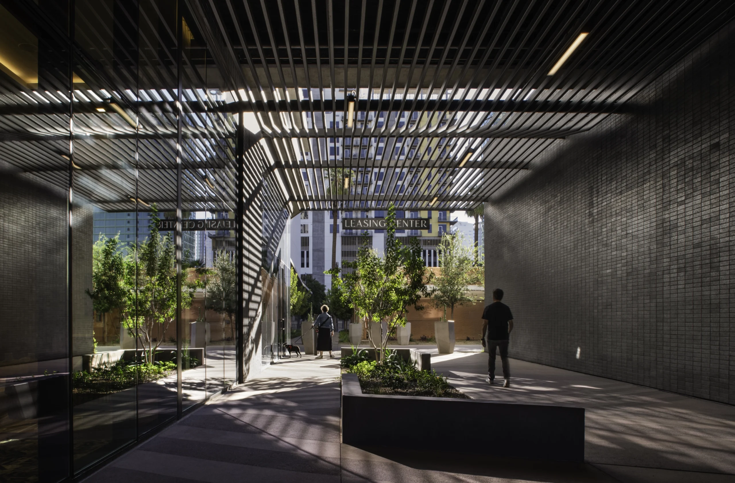 Mixed-use residential passageway connecting housing and commercial spaces with shaded walkways and integrated landscape design