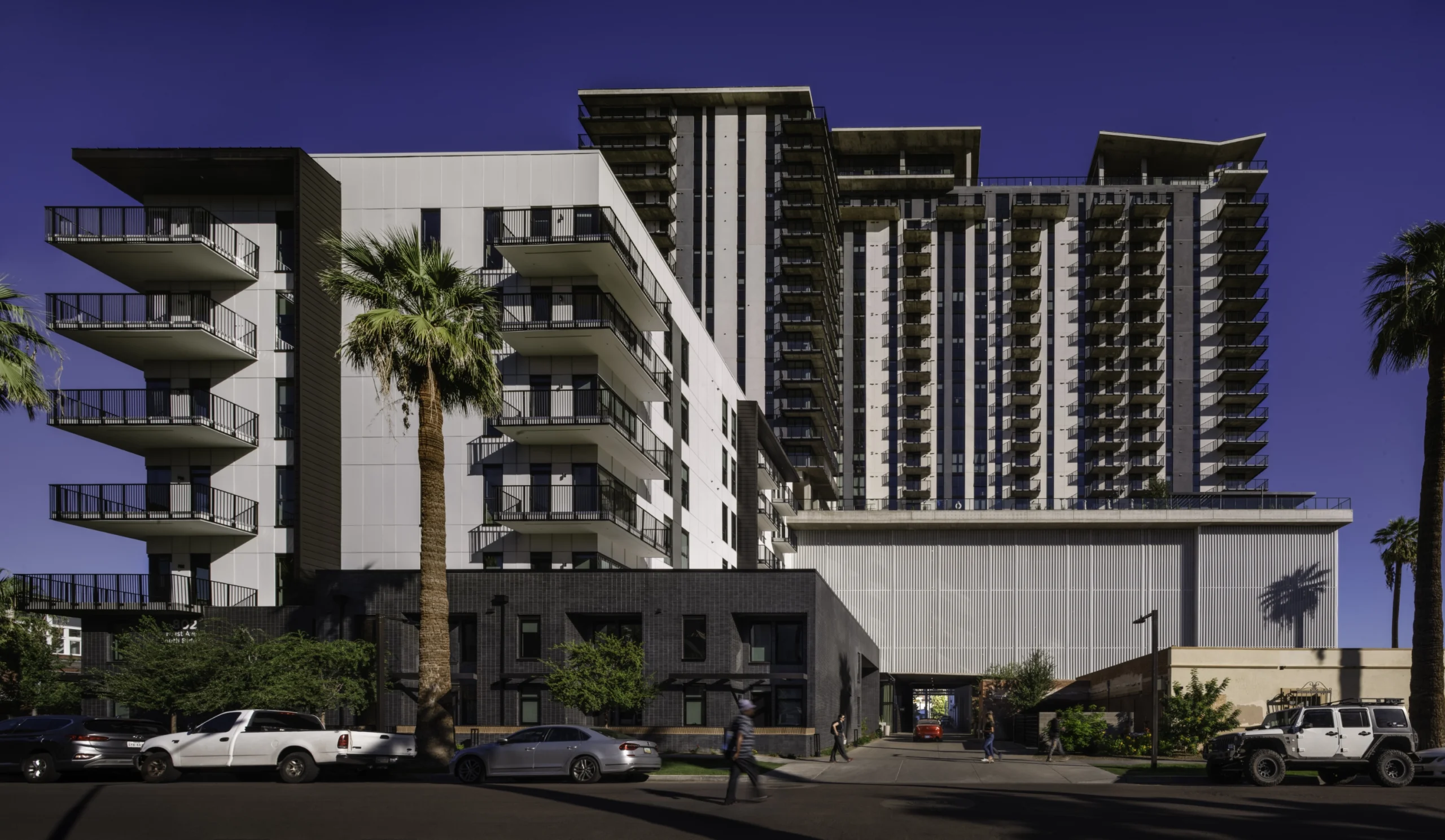 Mixed-use housing architecture with residential balconies above ground-floor commercial space along an active urban street