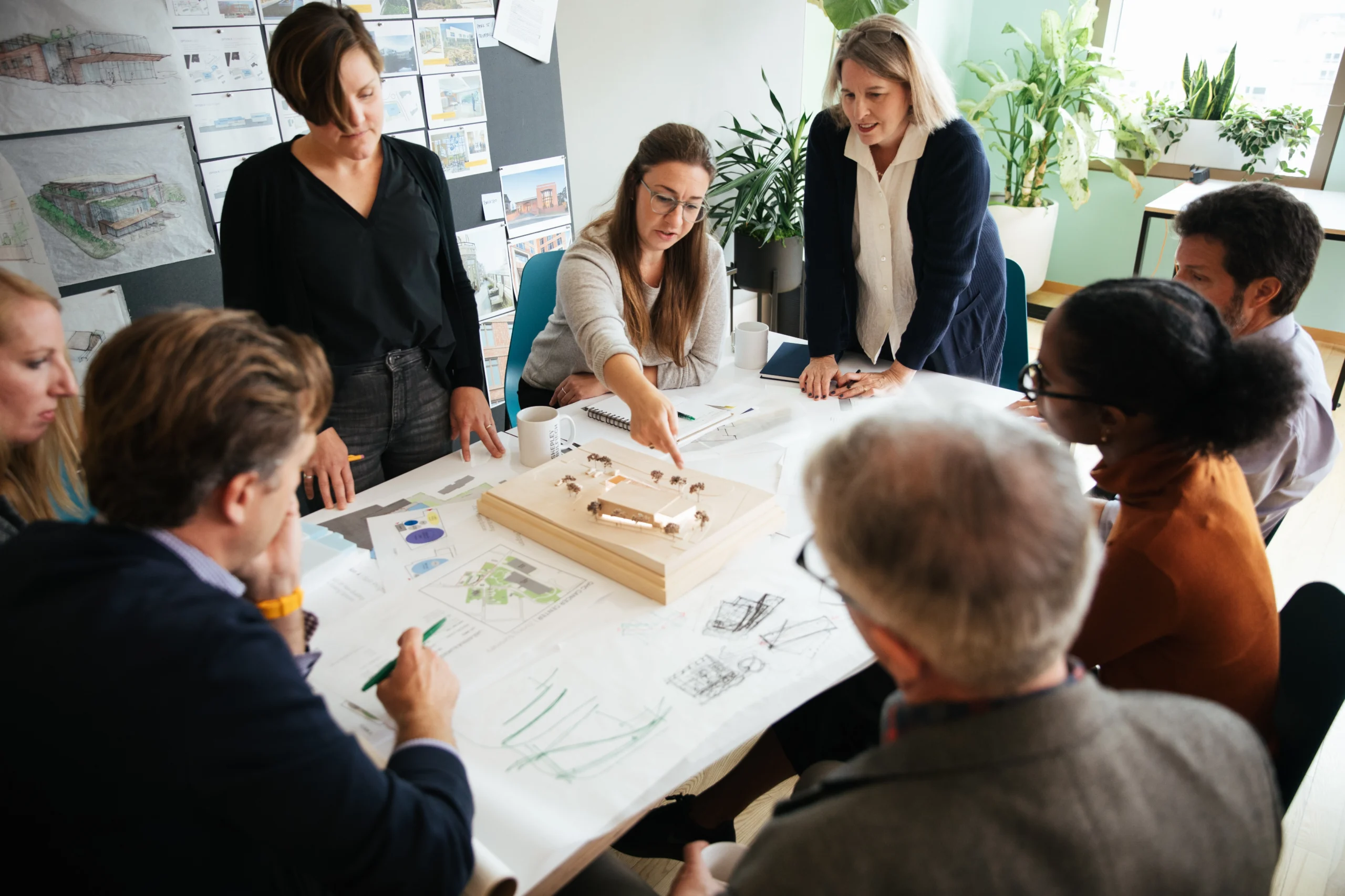Group of designers and stakeholders gather around model and collaborate